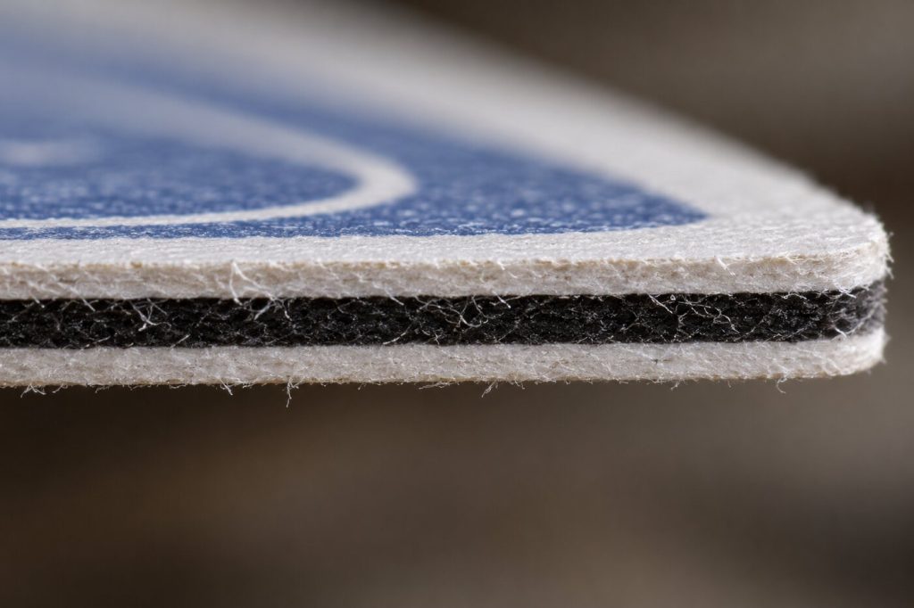 Tranche d'une carte épaisse vue de très près, avec une fine couche noire entre deux couches blanches